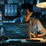 a focused it professional in a modern office, intently analyzing a sleek laptop screen filled with complex fortigate configuration data, illuminated by the cool glow of multiple tech gadgets and an organized workspace.